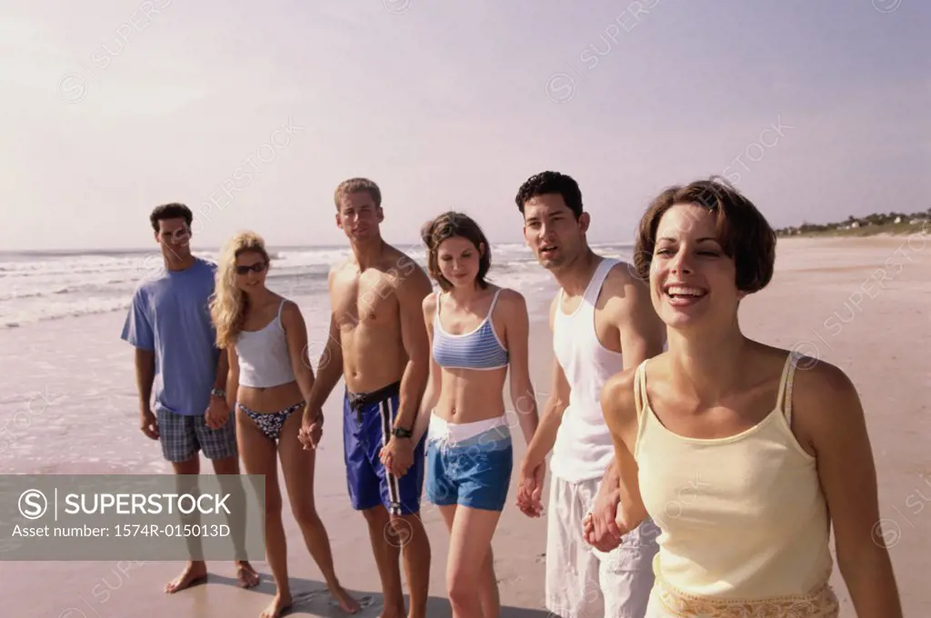 Group of young people holding hands on the beach