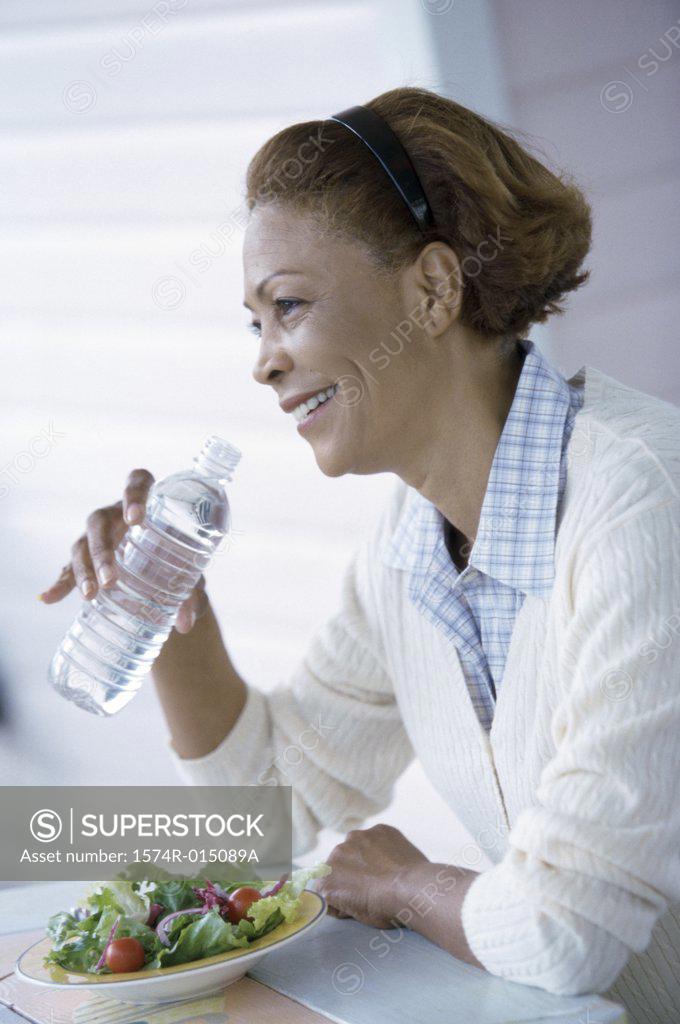 Stock Photo: 1574R-015089A Side profile of a mid adult woman drinking water from a water bottle