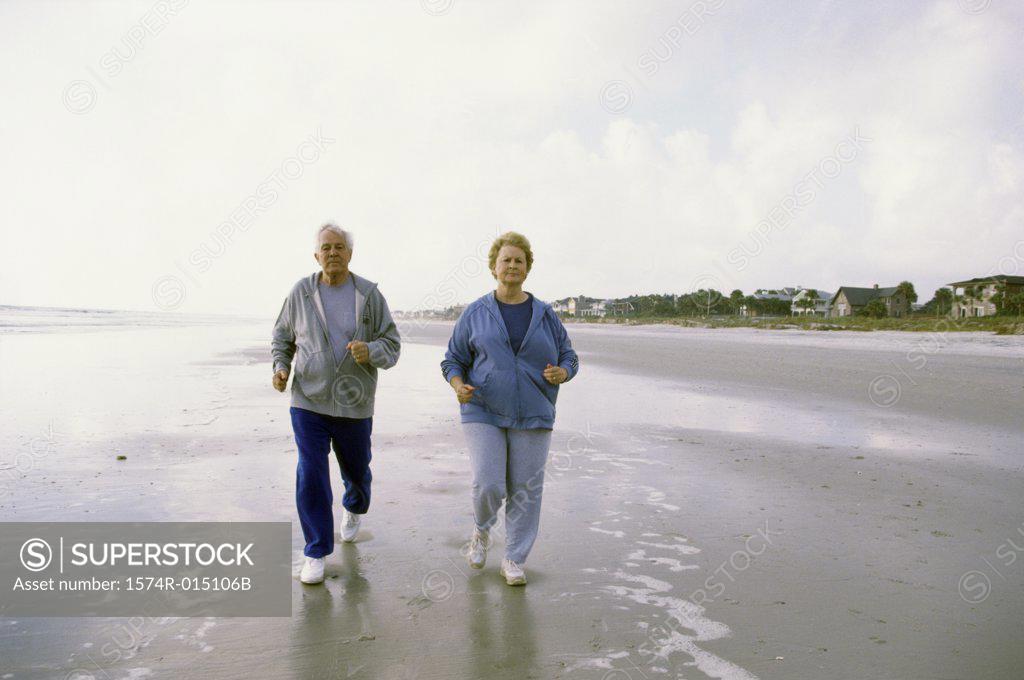 Stock Photo: 1574R-015106B Senior couple jogging on the beach