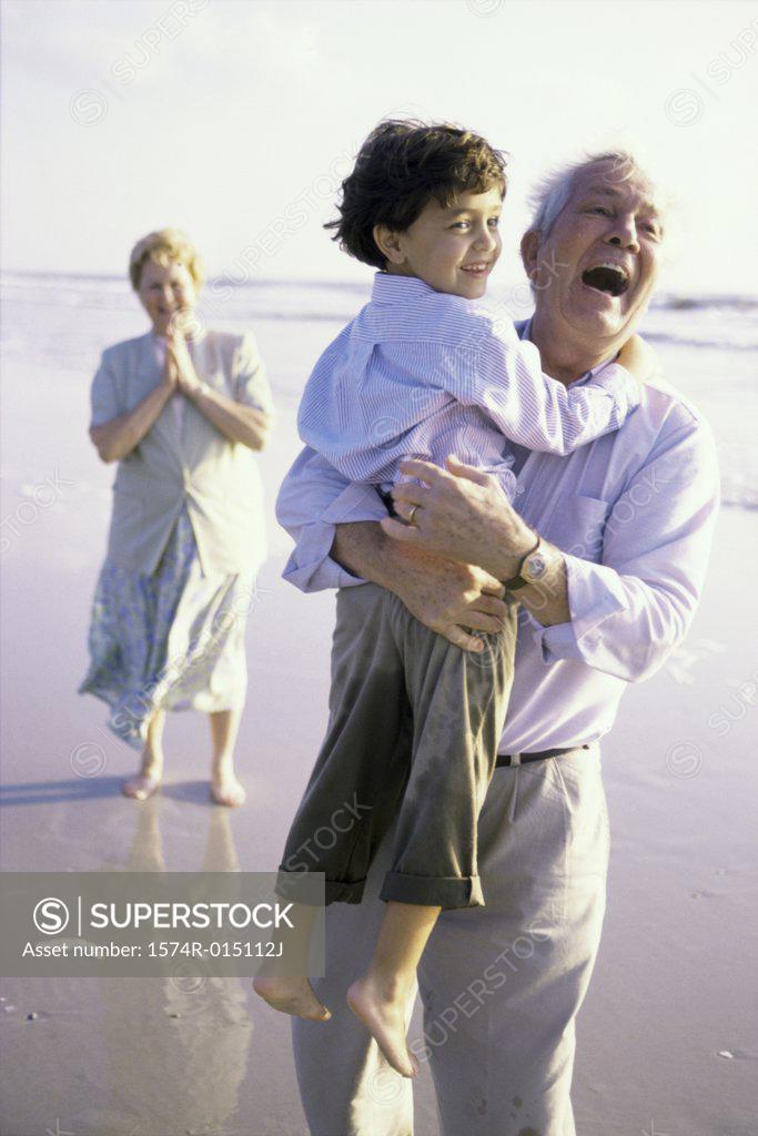 Stock Photo: 1574R-015112J Grandfather carrying his grandson on the beach
