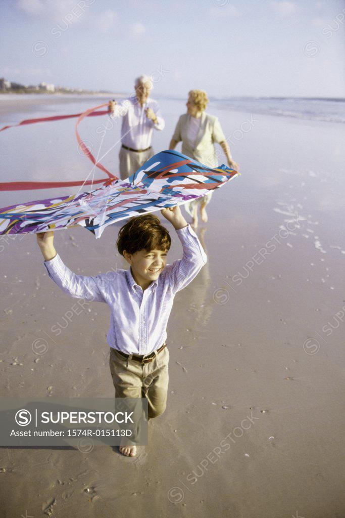 Stock Photo: 1574R-015113D Child flying a kite on the beach with his grandparents