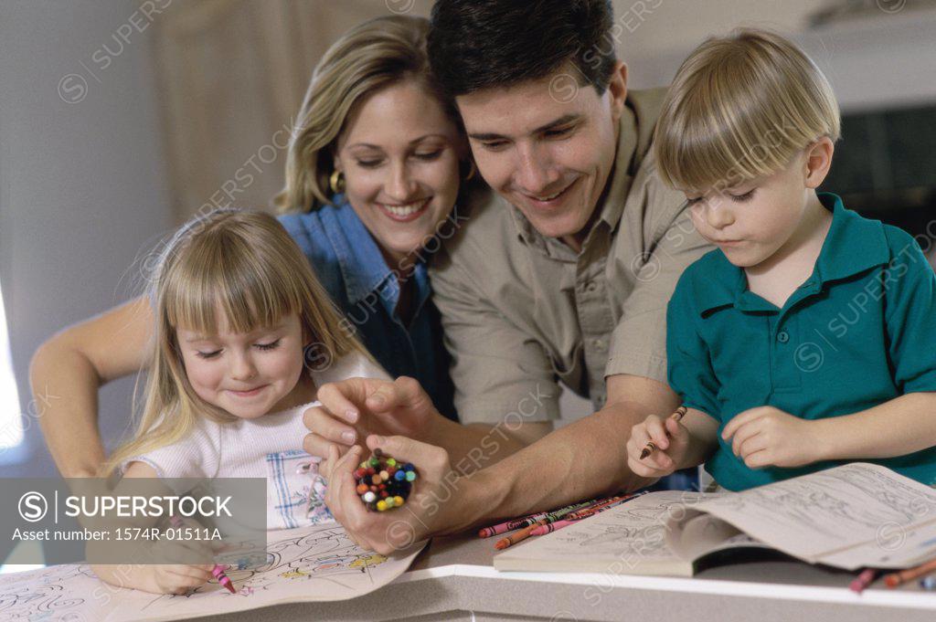 Stock Photo: 1574R-01511A Parents and their children drawing in a coloring book