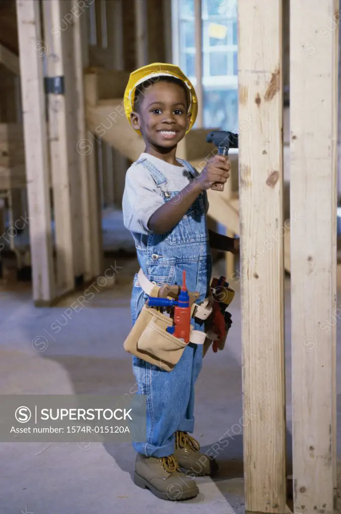 Portrait of a boy dressed as a construction worker holding a toy hammer