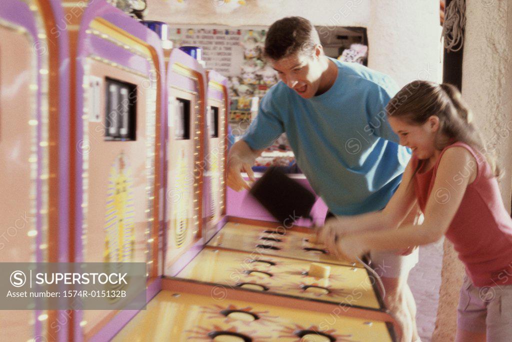 Stock Photo: 1574R-015132B Daughter playing games with her father standing beside her in an amusement park