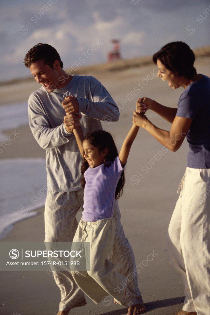 Stock Photo: 1574R-015198B Parents swinging their daughter on the beach