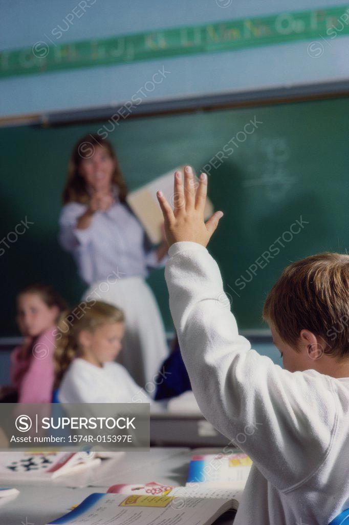 Stock Photo: 1574R-015397E Rear view of a schoolboy raising his hand in a classroom