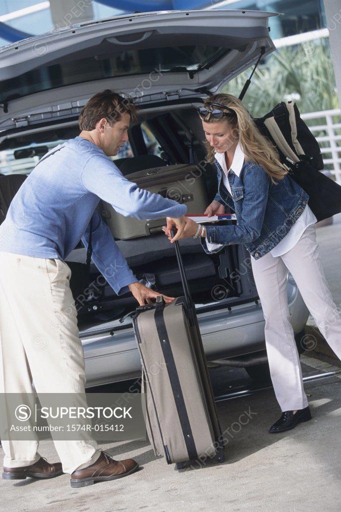 Stock Photo: 1574R-015412 Side profile of a young couple loading luggage into the back of a car