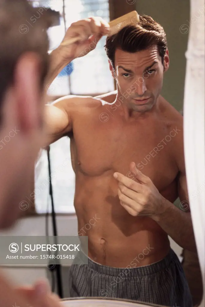 Close-up of a young man combing his hair in the bathroom