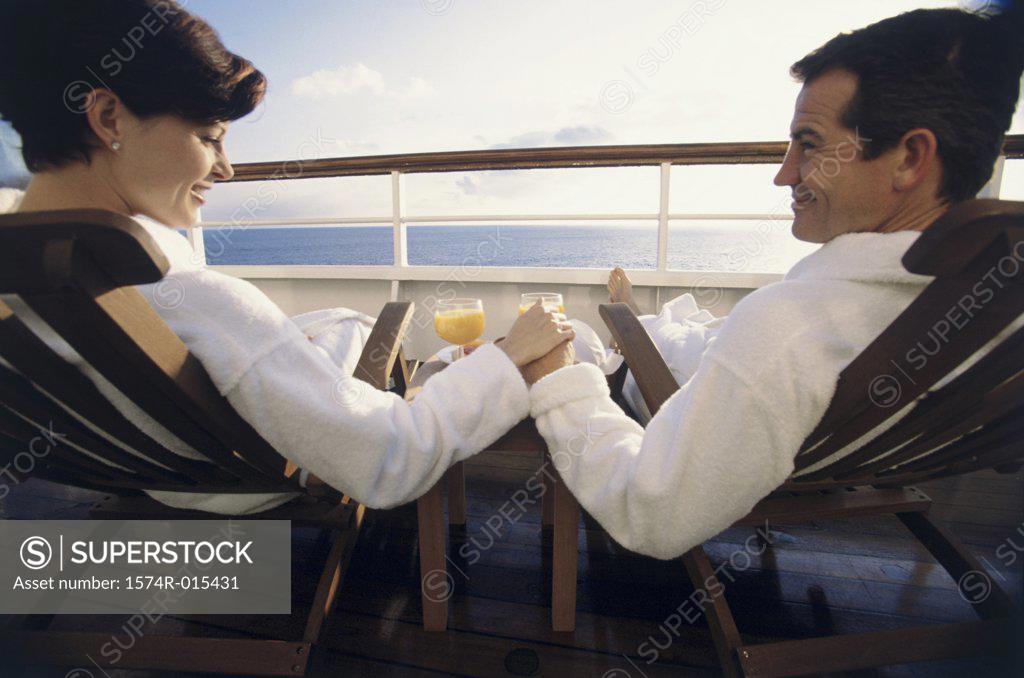 Stock Photo: 1574R-015431 Rear view of a mid adult couple sitting in deck chairs on a cruise ship