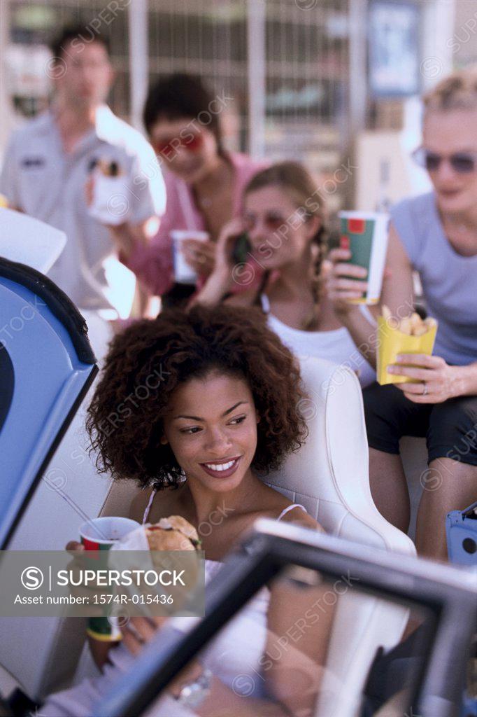 Stock Photo: 1574R-015436 High angle view of a young woman eating food with her friends in a car