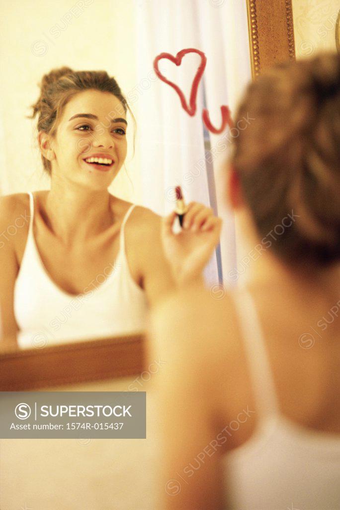 Stock Photo: 1574R-015437 Young woman drawing a heart on a mirror with red lipstick