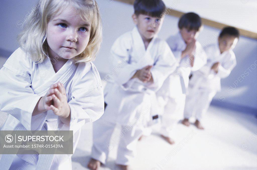 Stock Photo: 1574R-015439A Three boys and a girl learning martial arts