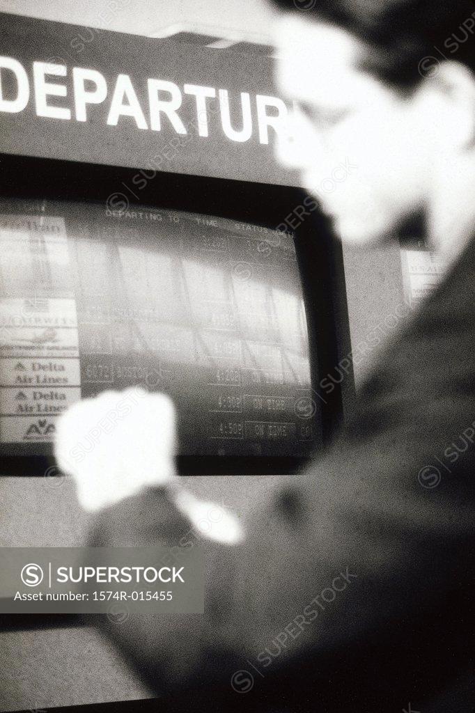 Stock Photo: 1574R-015455 Side profile of a businessman standing in an airport near the arrival and departure board