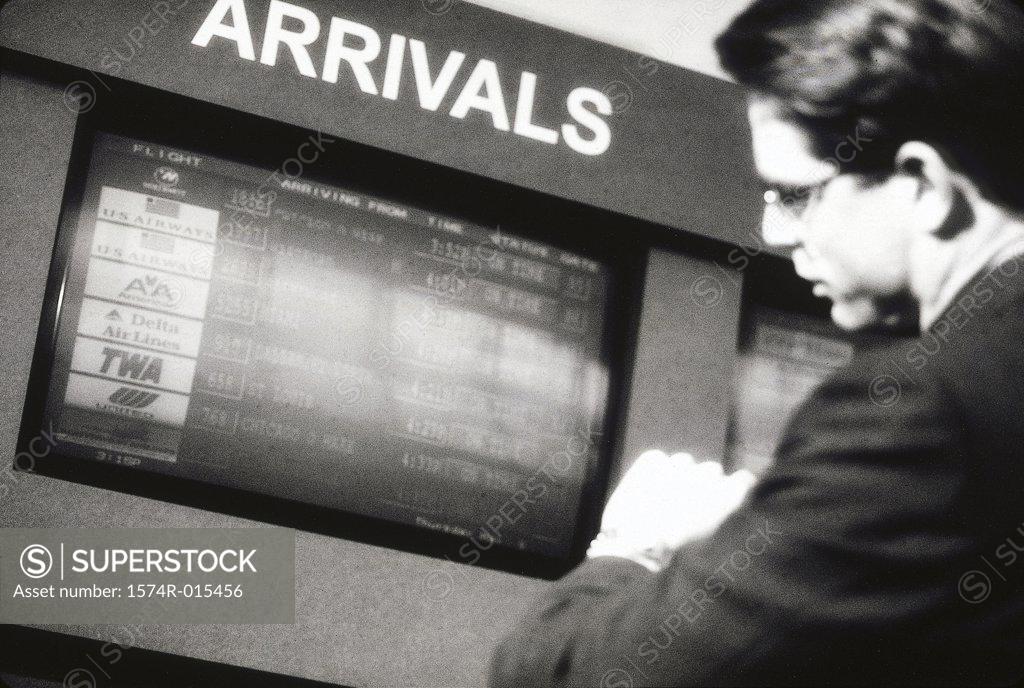 Stock Photo: 1574R-015456 Side profile of a businessman standing in an airport near the arrival and departure board