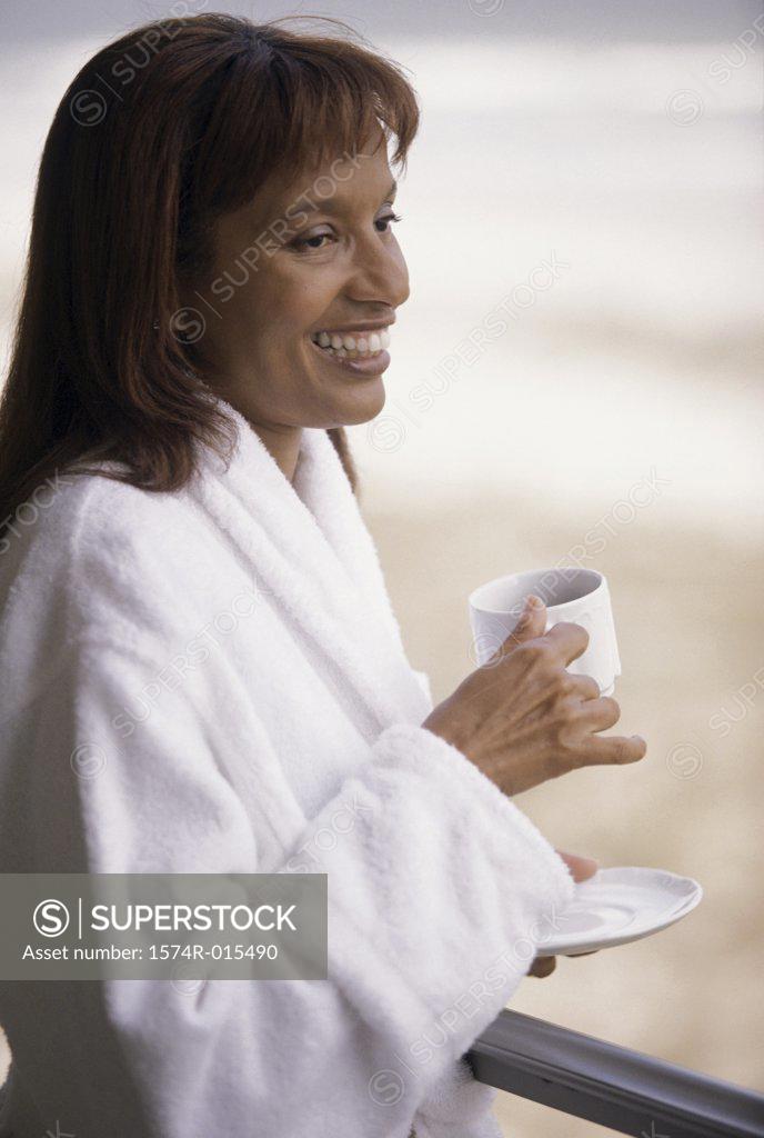 Stock Photo: 1574R-015490 Side profile of a mid adult woman holding a cup of coffee smiling