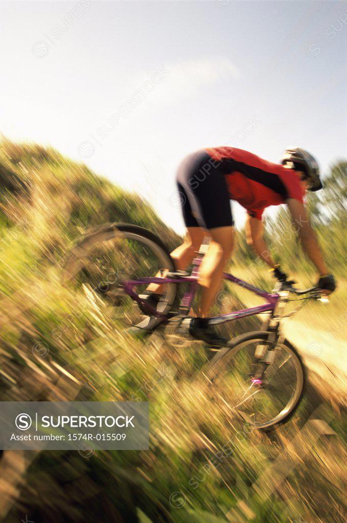 Stock Photo: 1574R-015509 Young man cycling down a hill