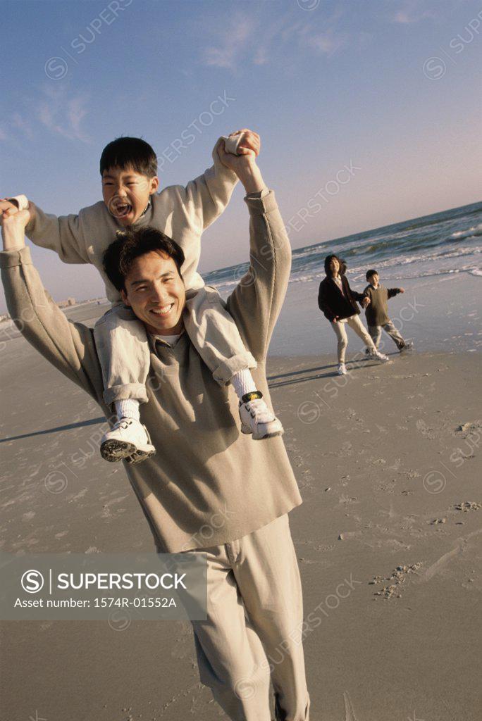 Stock Photo: 1574R-01552A Man carrying his son on his shoulders at the beach