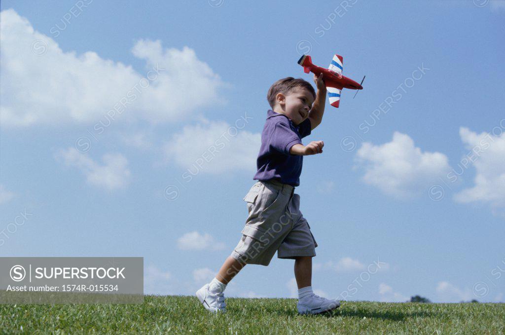 Stock Photo: 1574R-015534 Side profile of a boy playing with a toy airplane