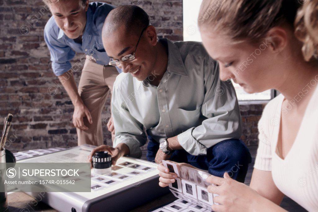 Stock Photo: 1574R-015542 Two businessmen and a businesswoman looking at slides