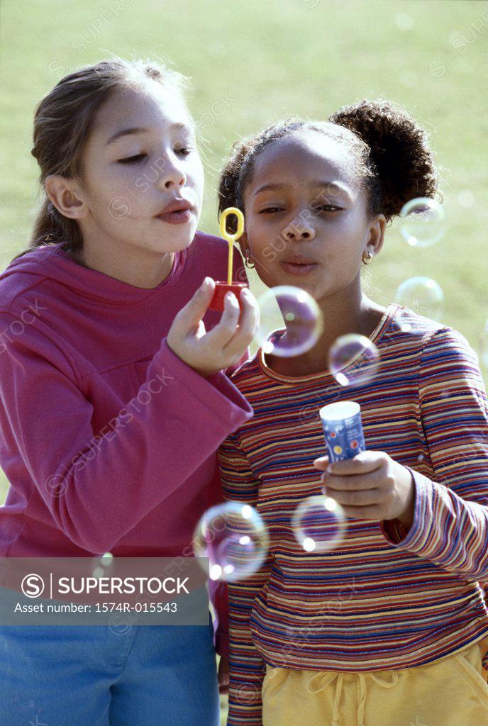 Stock Photo: 1574R-015543 Close-up of two girls blowing bubbles with a bubble wand