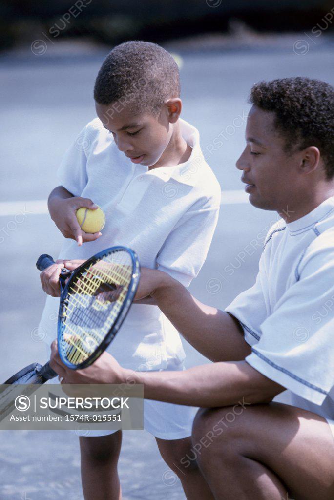 Stock Photo: 1574R-015551 Side profile of a father teaching his son to play tennis