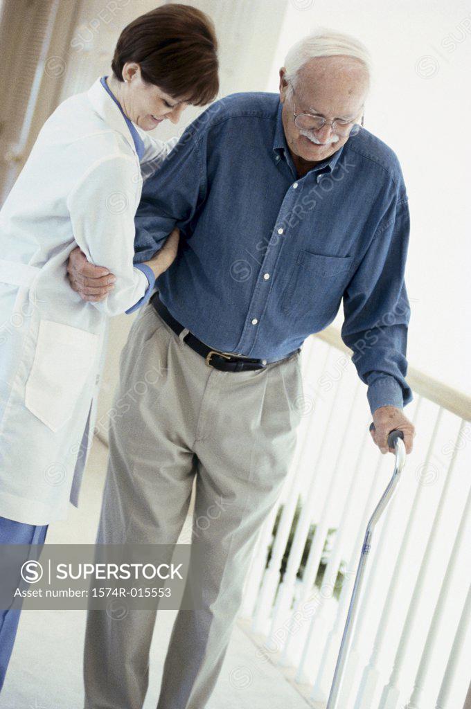 Stock Photo: 1574R-015553 Side profile of a female doctor helping a patient to walk with a cane