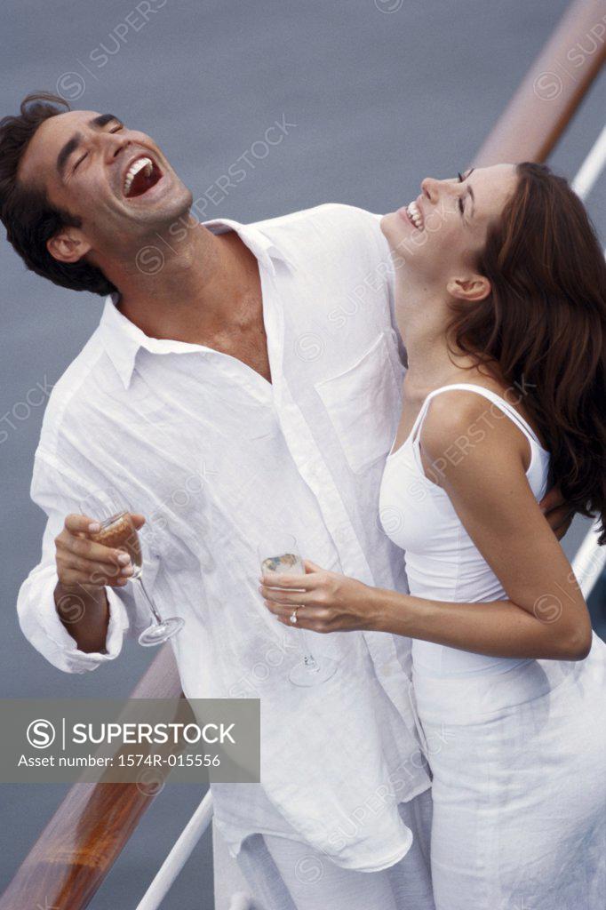 Stock Photo: 1574R-015556 High angle view of a young couple standing on the deck of a cruise ship and laughing
