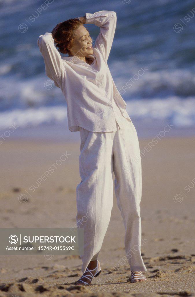 Stock Photo: 1574R-015569C Senior woman standing with her hands behind her head on the beach
