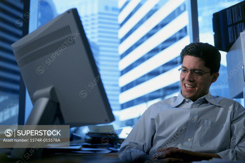 Stock Photo: 1574R-015578A Low angle view of a businessman sitting in front of a computer