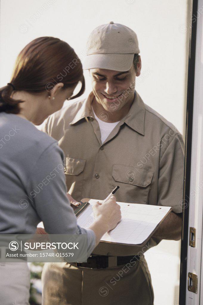 Stock Photo: 1574R-015579 Young woman signing for a delivery