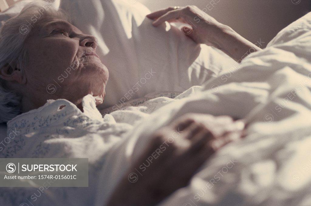 Stock Photo: 1574R-015601C Senior woman lying on a bed