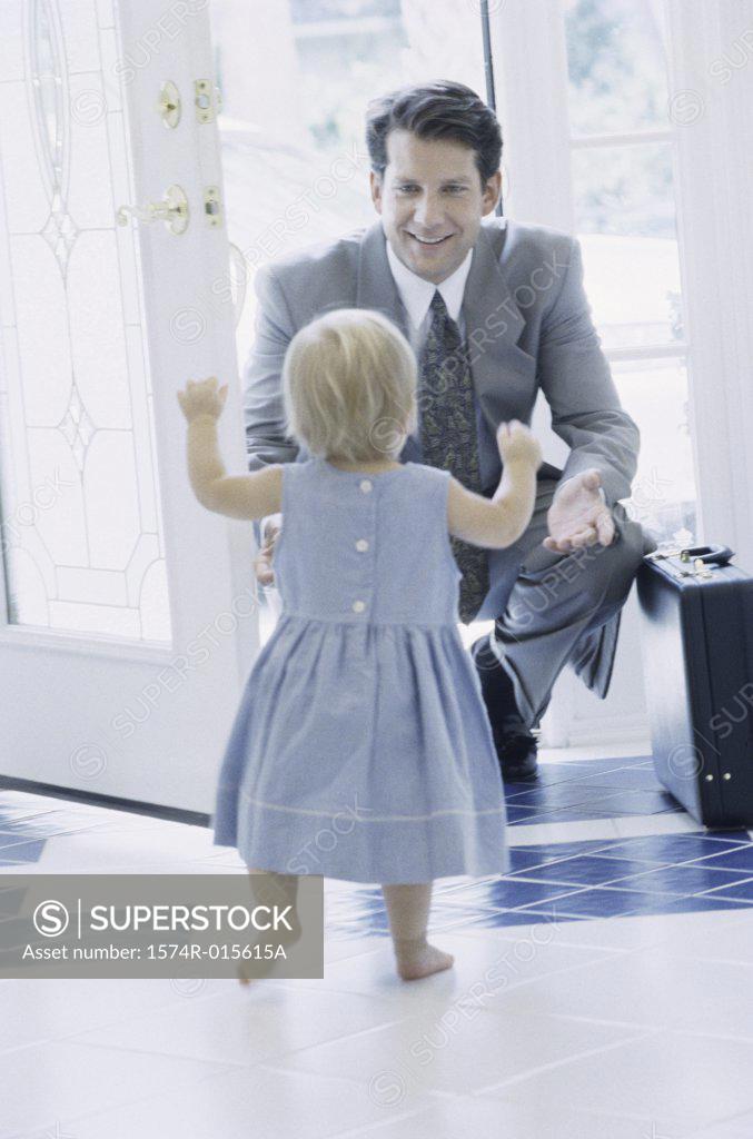 Stock Photo: 1574R-015615A Rear view of girl greeting her father at the front door