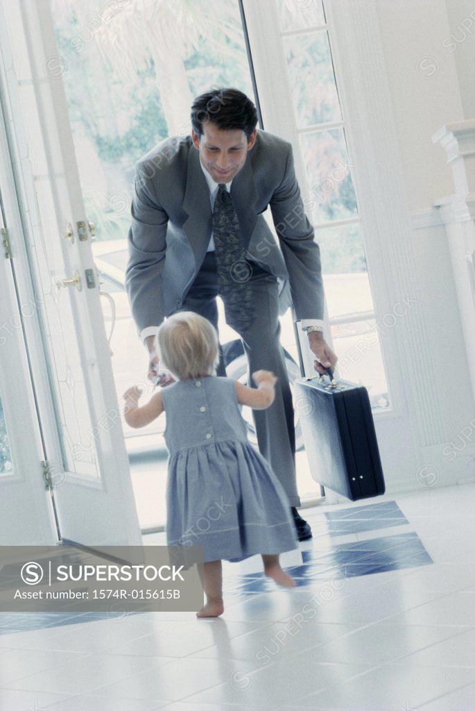 Stock Photo: 1574R-015615B Rear view of girl greeting her father at the front door