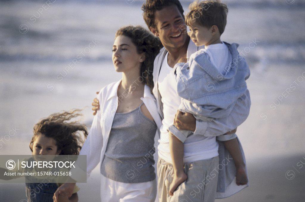 Stock Photo: 1574R-015618 Parents and their two children walking on the beach