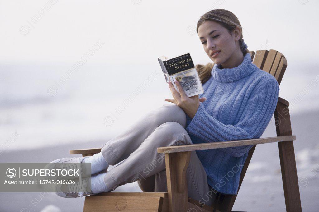 Stock Photo: 1574R-015636 Close-up of a young woman reading a book on the beach