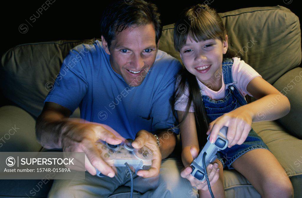 Stock Photo: 1574R-01589A Father and daughter playing a video game together