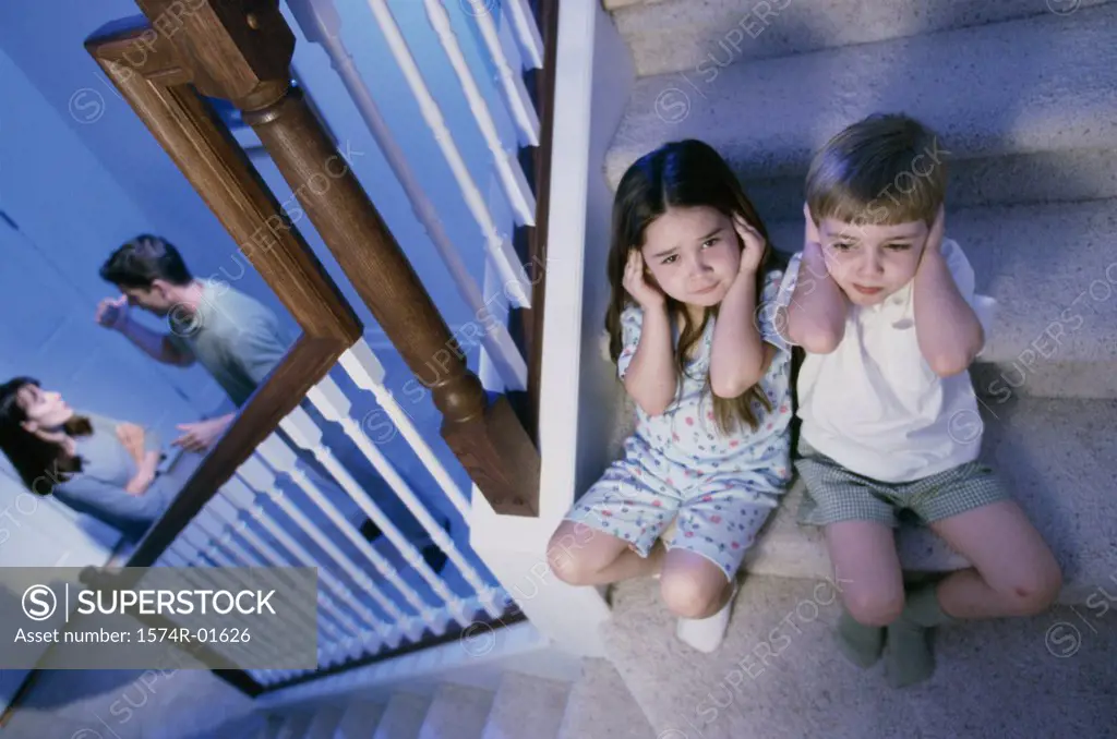 High angle view of a boy and girl listening to their parents fight