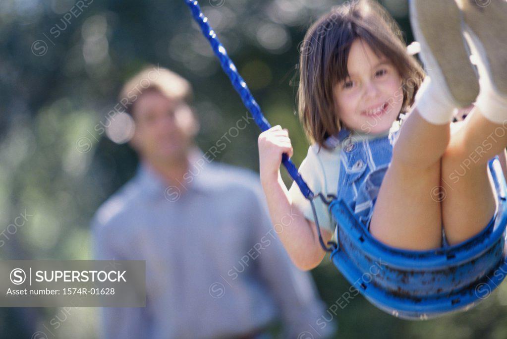 Stock Photo: 1574R-01628 Close-up of a girl on a swing with her father standing behind