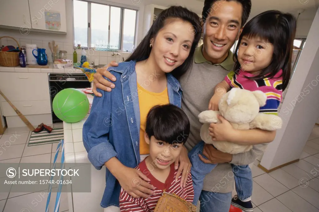 Portrait of a couple standing in the kitchen with their son and daughter