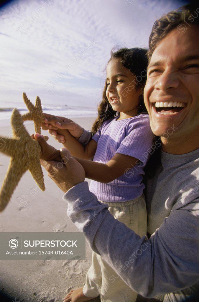 Stock Photo: 1574R-01640A Close-up of a man showing his daughter a starfish on the beach