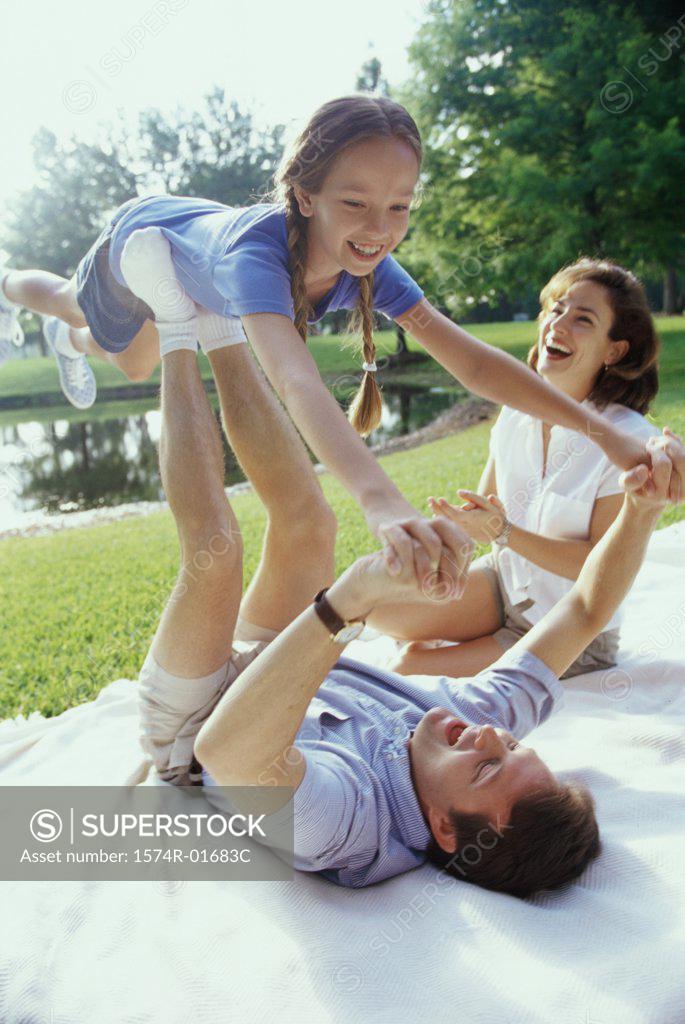 Stock Photo: 1574R-01683C Father and mother playing with their daughter on a lawn