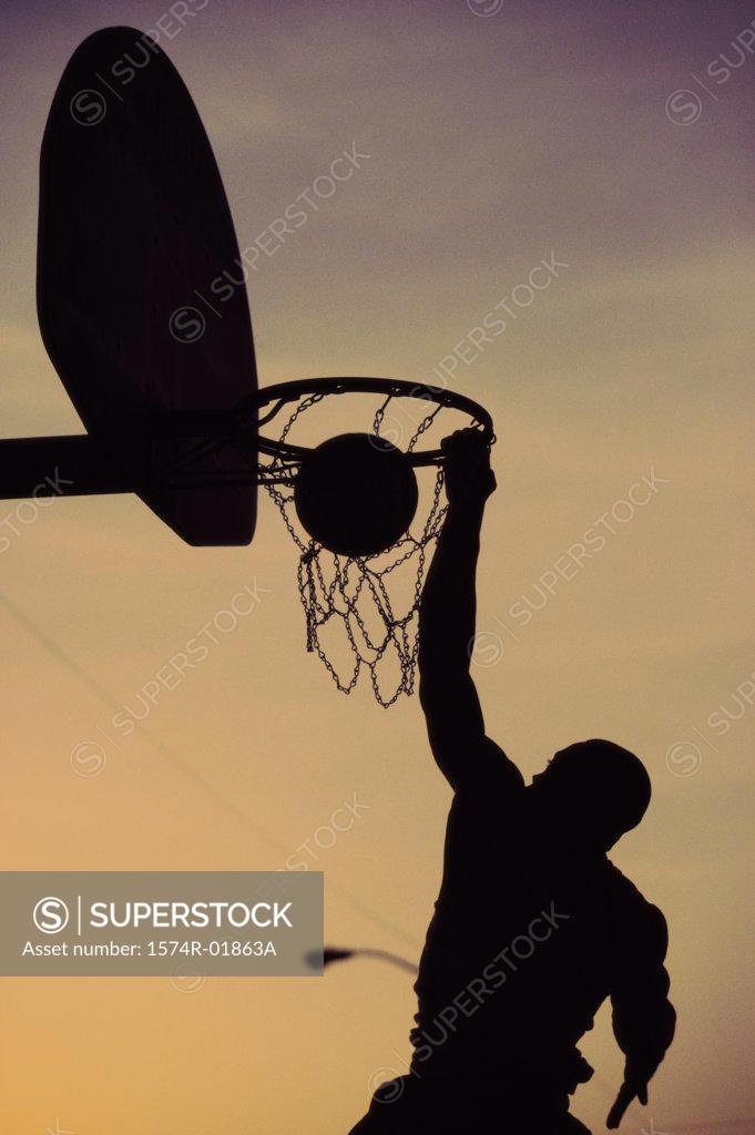 Stock Photo: 1574R-01863A Silhouette of a man slam dunking a basketball