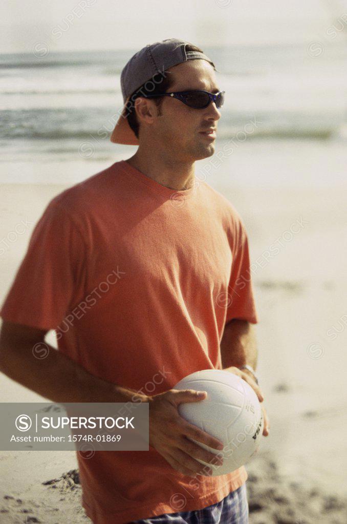 Stock Photo: 1574R-01869 Young man holding a volleyball on the beach