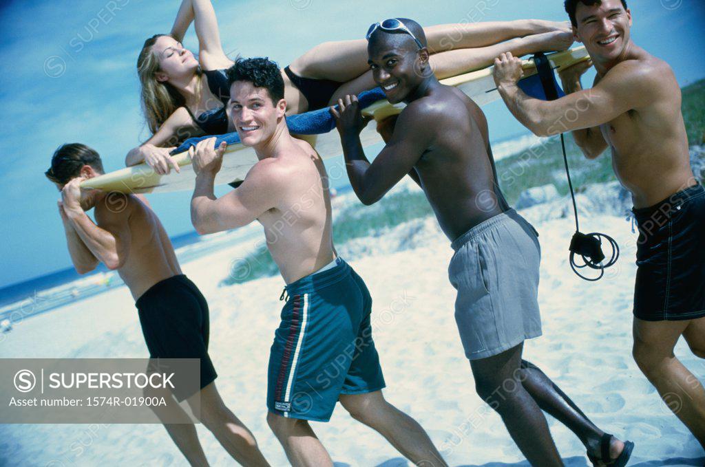 Stock Photo: 1574R-01900A Young men carrying a woman on a surfboard