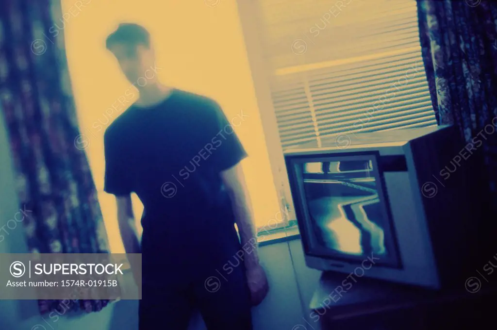 Young man standing beside a television