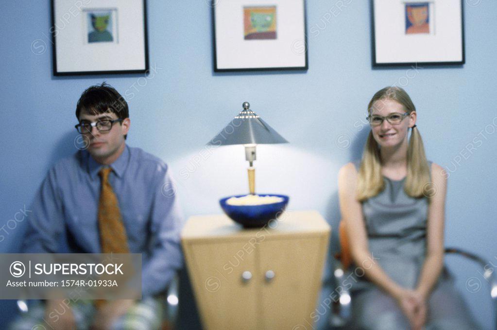 Stock Photo: 1574R-01933A Teenage boy and girl sitting on chairs and waiting