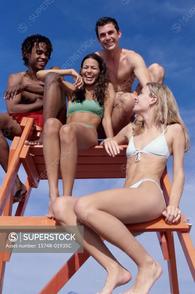 Low angle view of a group of teenagers sitting on a lifeguard tower