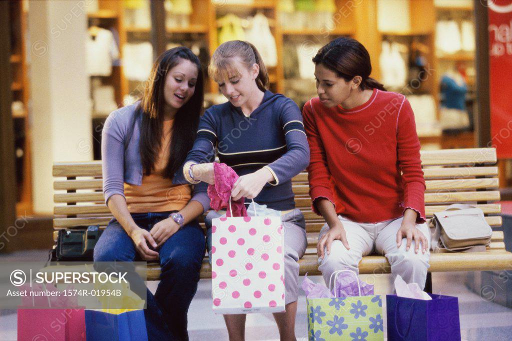 Stock Photo: 1574R-01954B Three teenage girls looking at clothes in shopping bags