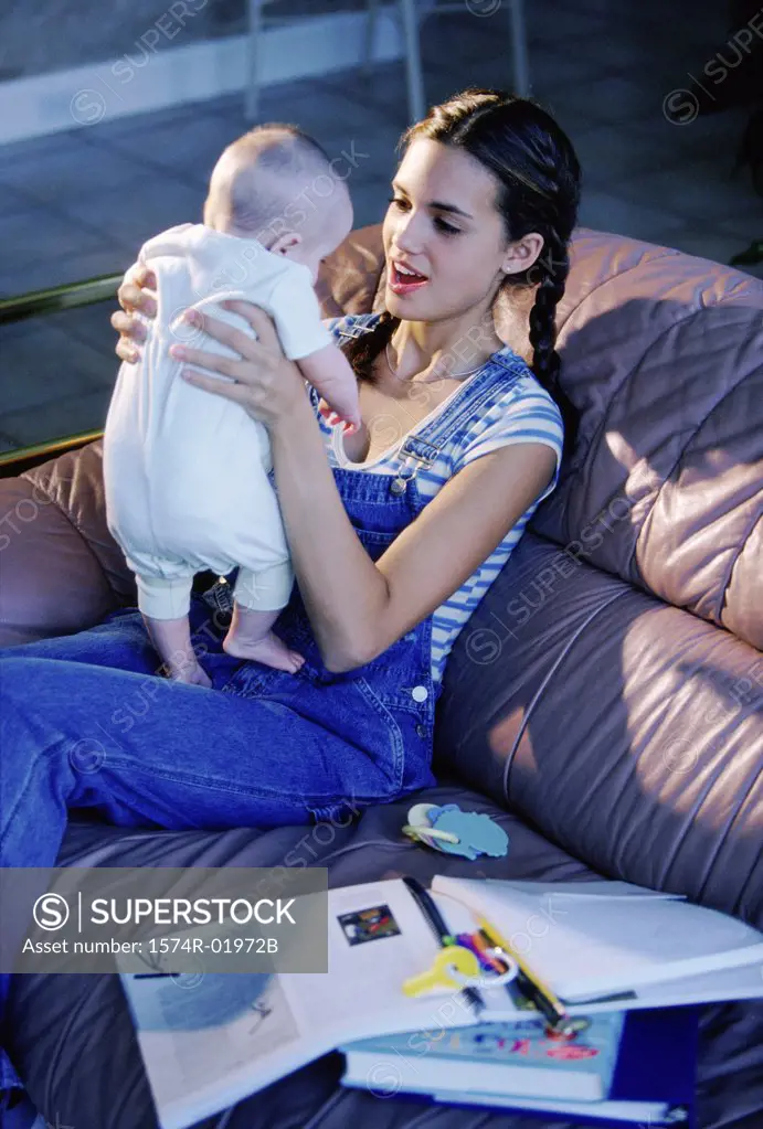 Teenage girl sitting on a couch holding a baby boy