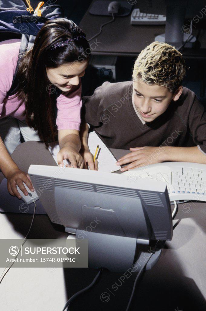 Stock Photo: 1574R-01991C Teenage boy and a teenage girl in front of a computer monitor